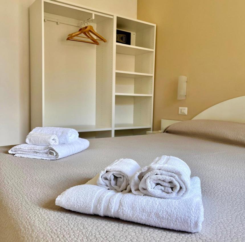 Camera accogliente con letto ordinato e asciugamani bianchi, atmosfera serena.