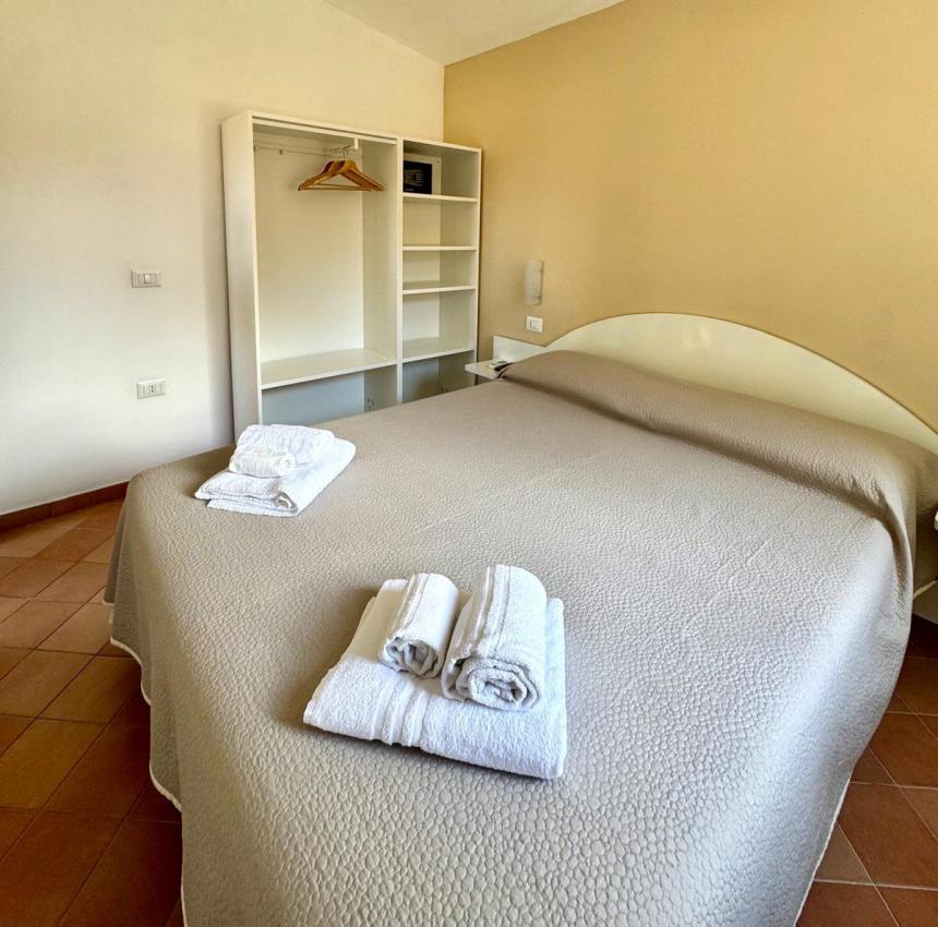 Camera accogliente con letto matrimoniale, lenzuola fresche e armadio aperto.