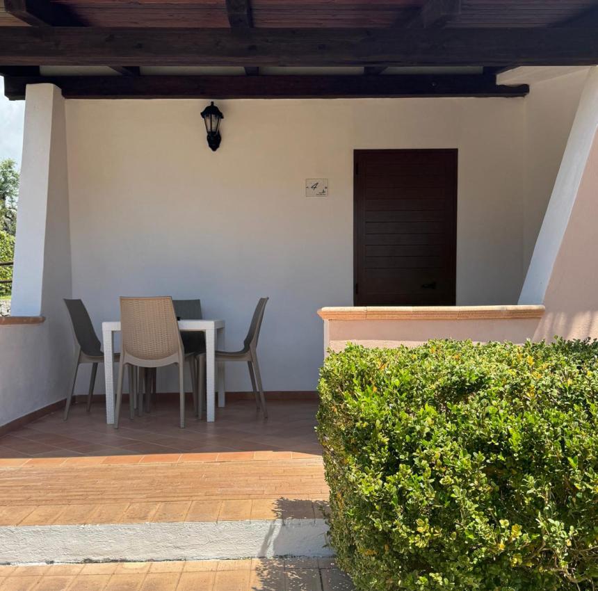 Veranda accogliente con tavolo, sedie e piante verdi, atmosfera tranquilla e rilassante.